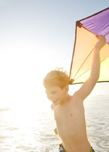 Beach, child and running with kite for playing,...