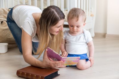 Mother reading book to her 10 months old baby boy on...