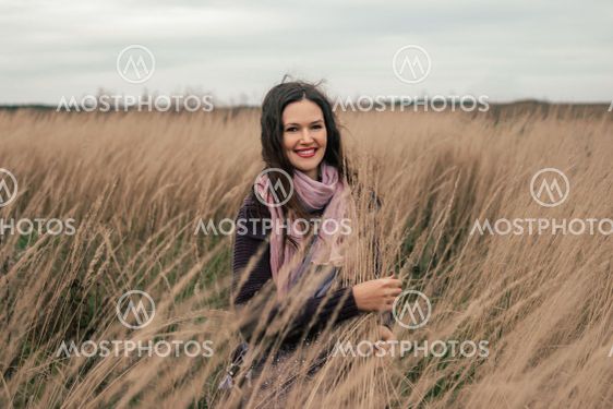 beautiful young woman standing among ripe ears of wheat