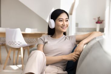Serene Asian woman listen music though wireless headphones
