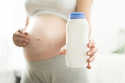 Closeup of pregnant woman holding creme container with...