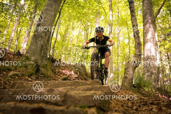 kvinna cyklar nerför trappa i skogen