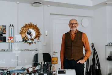 Portrait of smiling male owner with hand in pocket...
