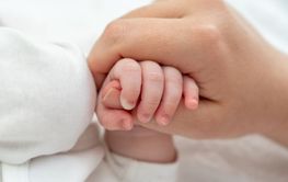 Newborn's delicate grip on mother's thumb exudes trust....