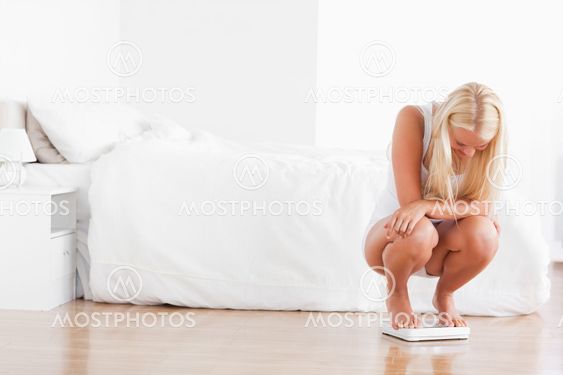 Blonde woman squatting on a weighing machine