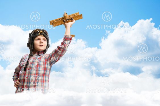 Boy in helmet pilot playing with a toy airplane