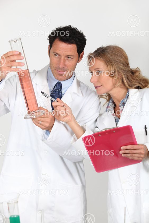 Laboratory technicians examining pink liquid