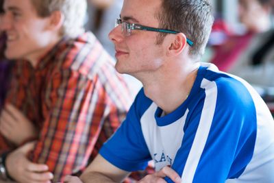 Handsome college student sitting in a classroom full of...