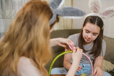Mother And Daughter Decorating Easter Basket Together.