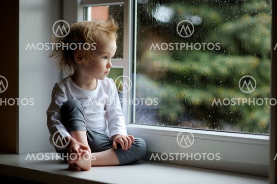 Adorable toddler girl looking though the window
