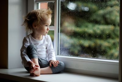 Adorable toddler girl looking though the window