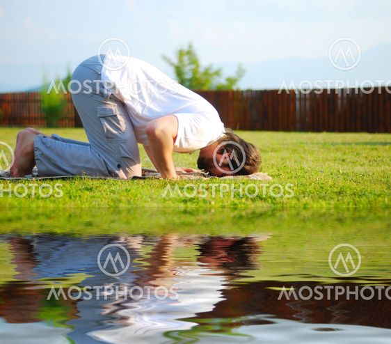 Young happy man on meadow praying