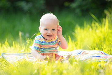 Baby boy with apple on family garden picnic
