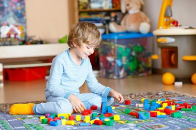 Little blond child playing with colorful wooden blocks...