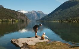 Father and daughter standing on rock by lake