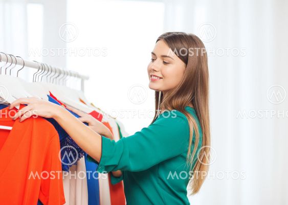 happy woman choosing clothes at home wardrobe