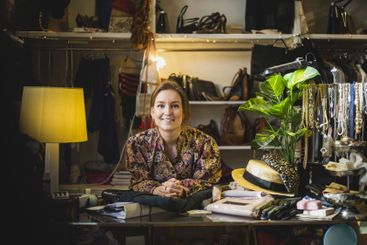 Caucasian female entrepreneur leaning on table in boutique