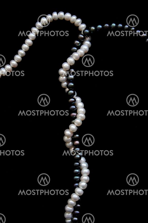 White and black pearls on a black velvet background