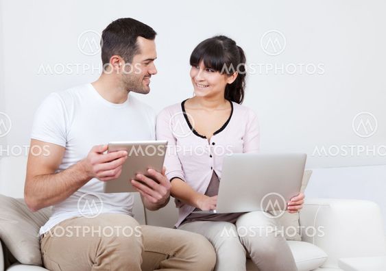 Young couple using laptops in couch