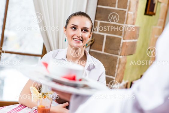 waiter brings a dish for a nice woman