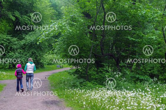 mother and daughter walking in the forest holding hands