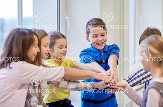 group of smiling school kids putting hands on top