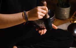 Practitioner uses singing bowls for meditation in a...