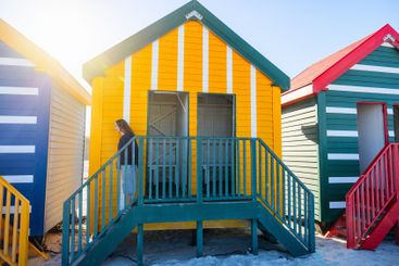 Teenager near colorful Muizenberg Beach huts.
