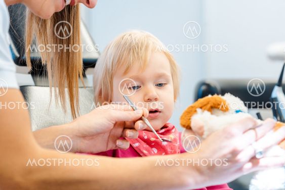 Dentist explaining treatment to a child using a plush toy
