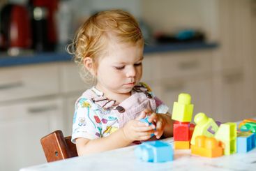 Adorable toddler girl with educational toys in nursery...