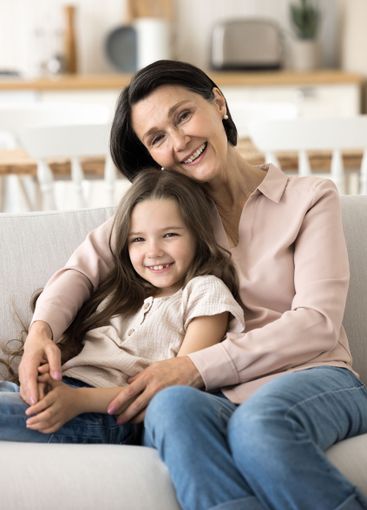 Little girl sitting on sofa leaning back to beloved grandma