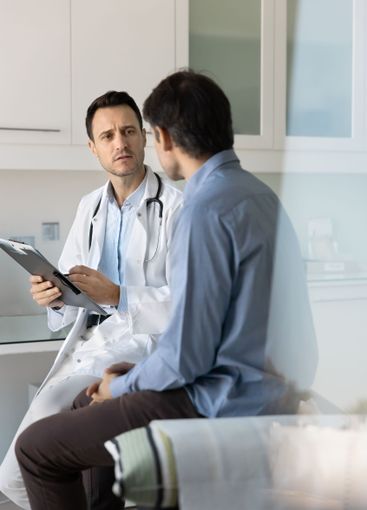 Focused concerned doctor examining male patient, working...