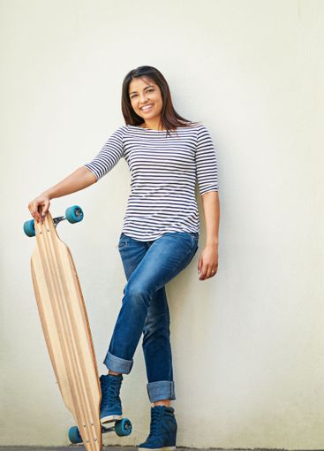 Portrait, smile and woman with skateboard, wall and girl...