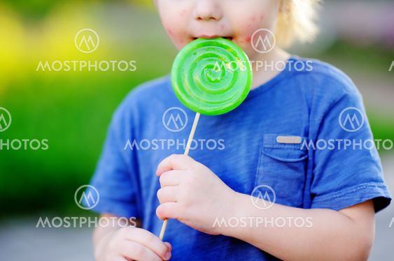Child with allergic reaction eating big green lollipop