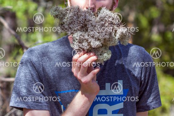Young man holding lichen as fake beard