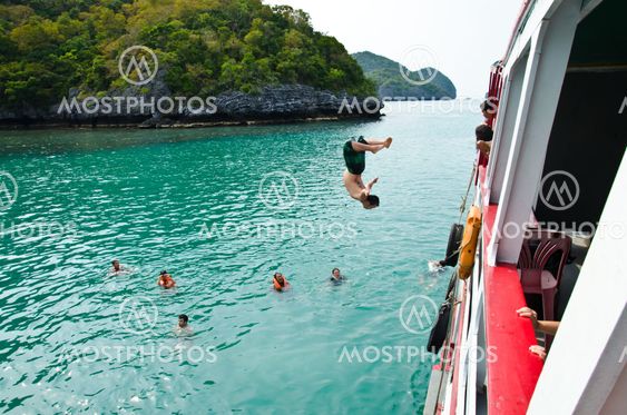 Travellers leap from the deck into the water.