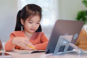 A young girl is concentrating on her homework with a...