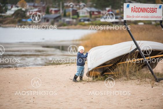 Pojke på strand vid räddningsbåt