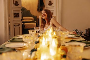 A cute teenager is sitting and laughing at a festive...