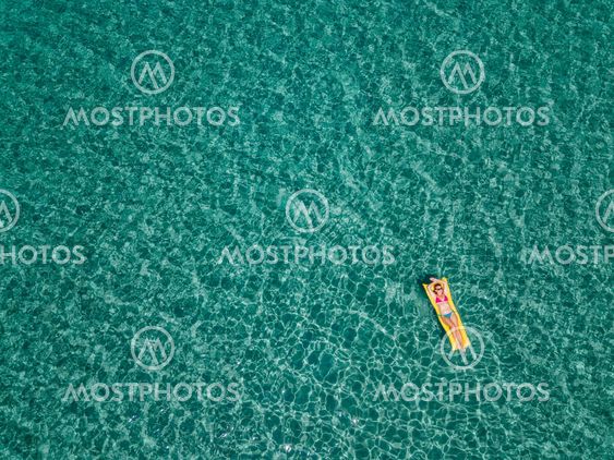 Aerial view of woman floating on the water mattress in...
