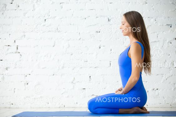 Young attractive woman in vajrasana pose, white studio backgroun