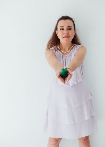Beautiful brunette woman holding a green candle in her...