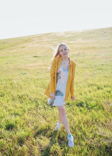 Beautiful blonde woman in summer dress walking in...