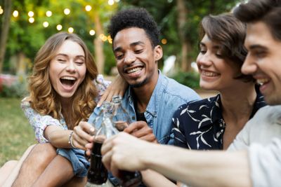 Happy young friends outdoors in park having fun talking...