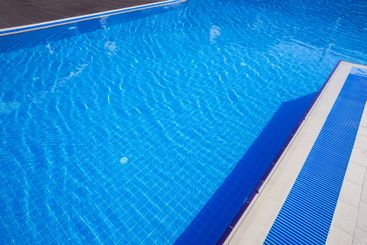 Crystal clear swimming pool under bright sunlight with...