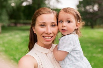 mother with baby girl taking selfie at summer park