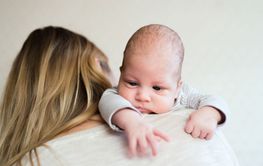 Unrecognizable young mother holding baby son in her arms