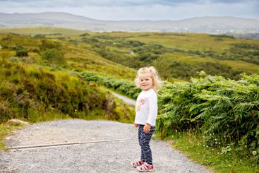 Cute little happy toddler girl running on nature path in...