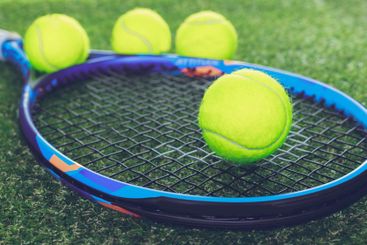 Bright yellow tennis balls bounce near a colorful racket...