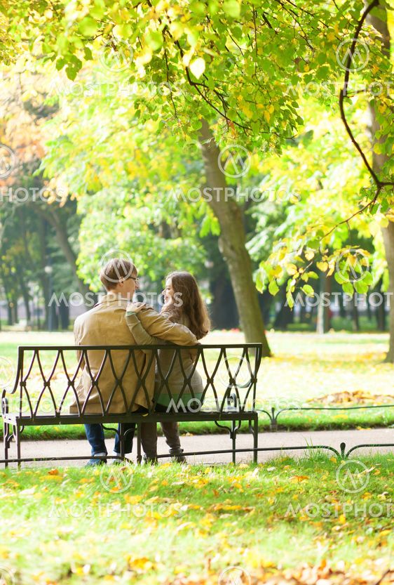 Couple sitting on a bench in park on a spring or fall day